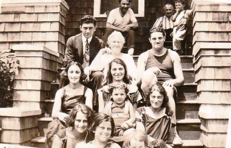Old phot of a family gathered on the steps of their home