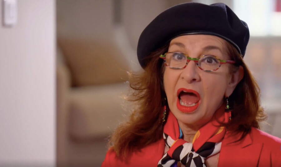 Adrian Leeds, mouth agape, gobsmacked, wearing her signature beret and a red jacket