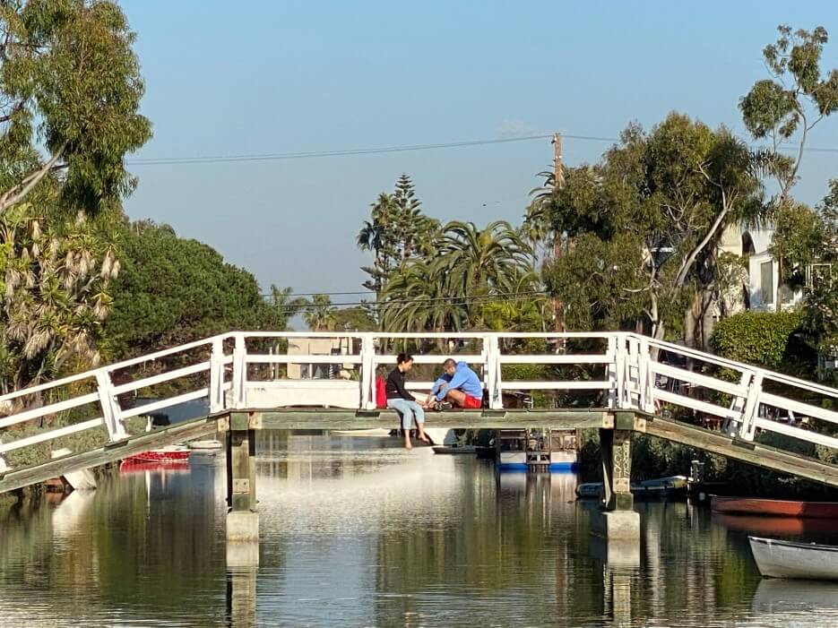 A white bridge over a Venice canals with people on it