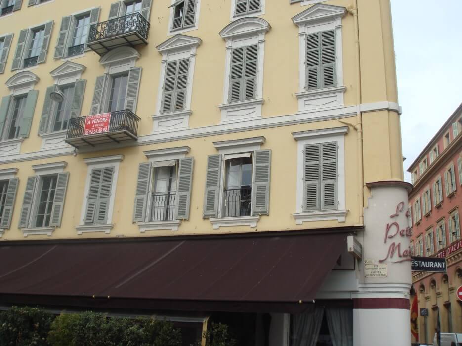 Building facade in Paris with an apartment for sale sign