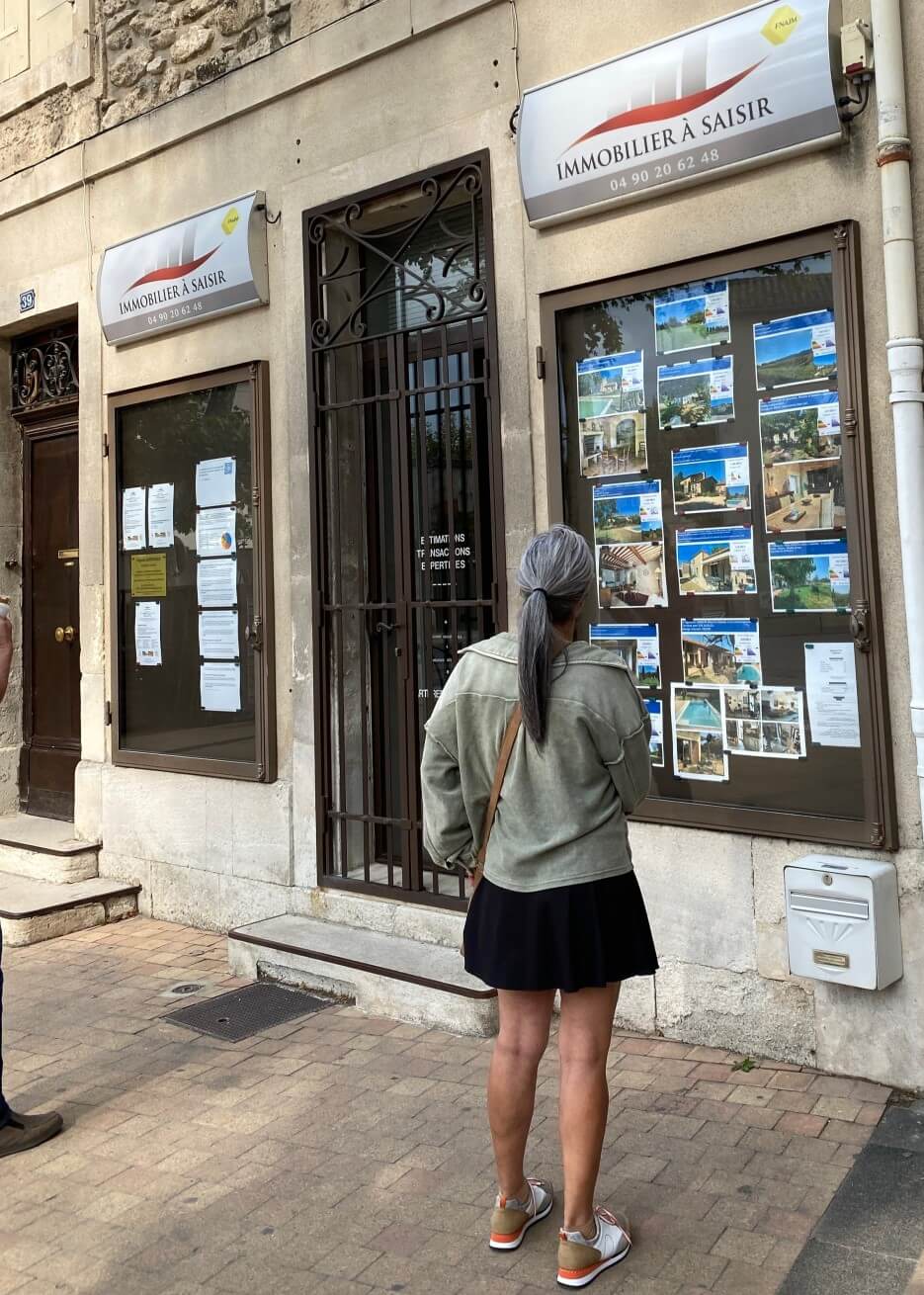 Woman looking at the property listings in the window of a real estate office In Paris