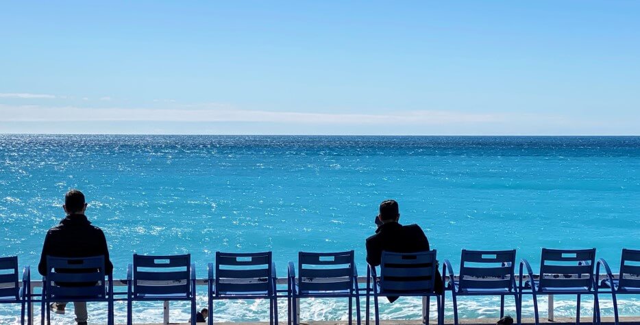 People sitting in the chaises bleu along the beach in Nice, France
