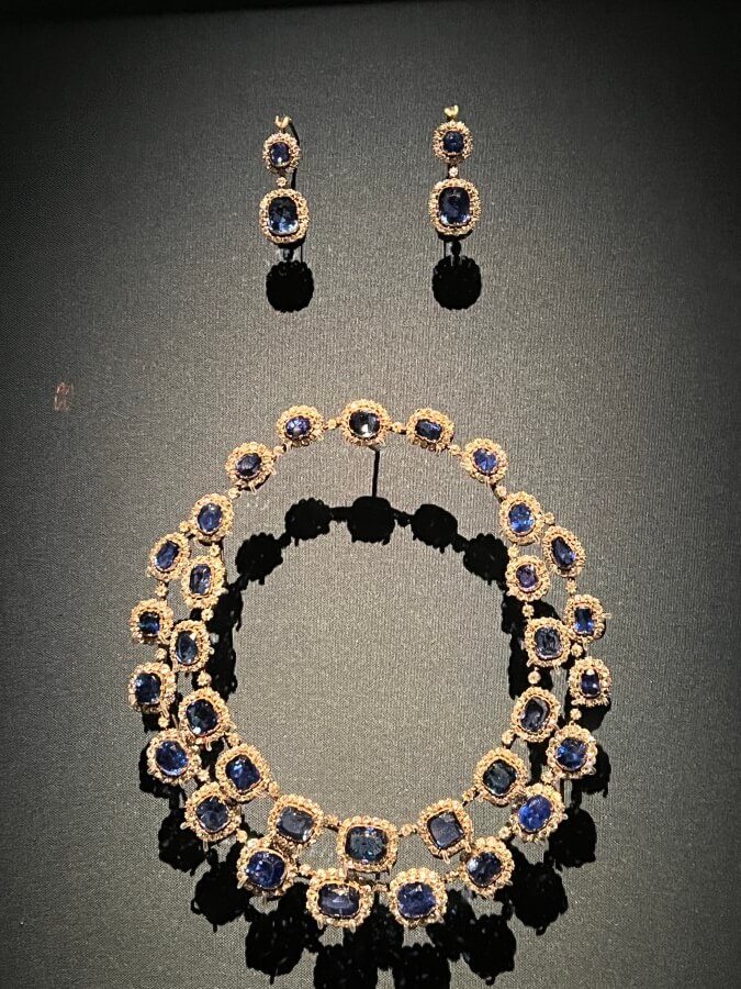 Diamond earrings and necklace set at the Al Thani collection oh exhibit at Promotional poster for the Joyaux Dynastique exhibit at The Hôtel de la Marine in Paris, France
