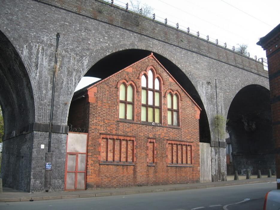 A building with a peaked roof built under a rounded arch: square peg, round hole