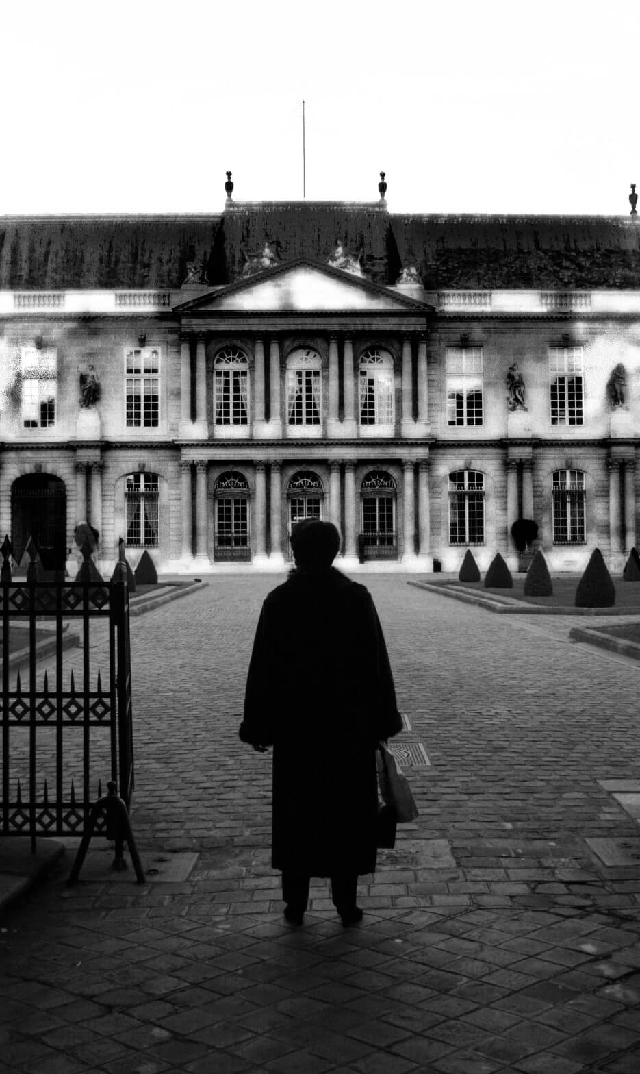 Black and white photo by Erica Simone depecting a woman staring at a large chateau in France