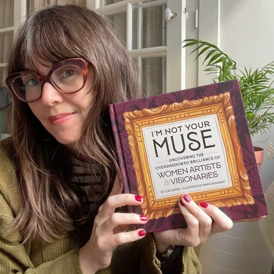 Maria Krasinski holding a copy of her book, I'm Not Your Muse