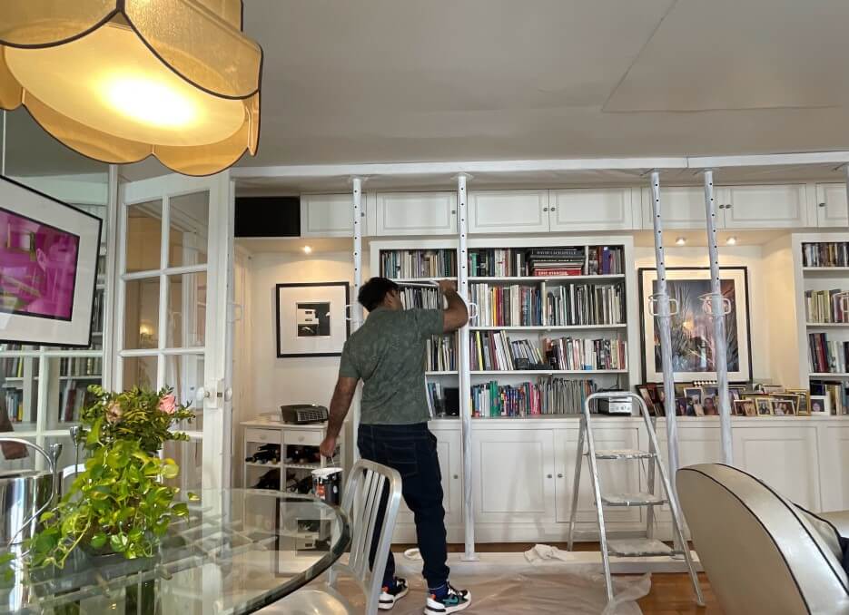 A painter painting the poles in Adrian Leeds' apartment white