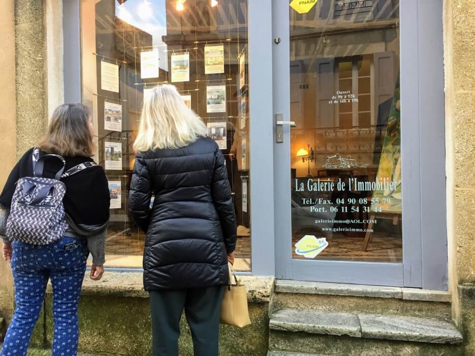 Two women staring at the property listings for a real estate agency in France