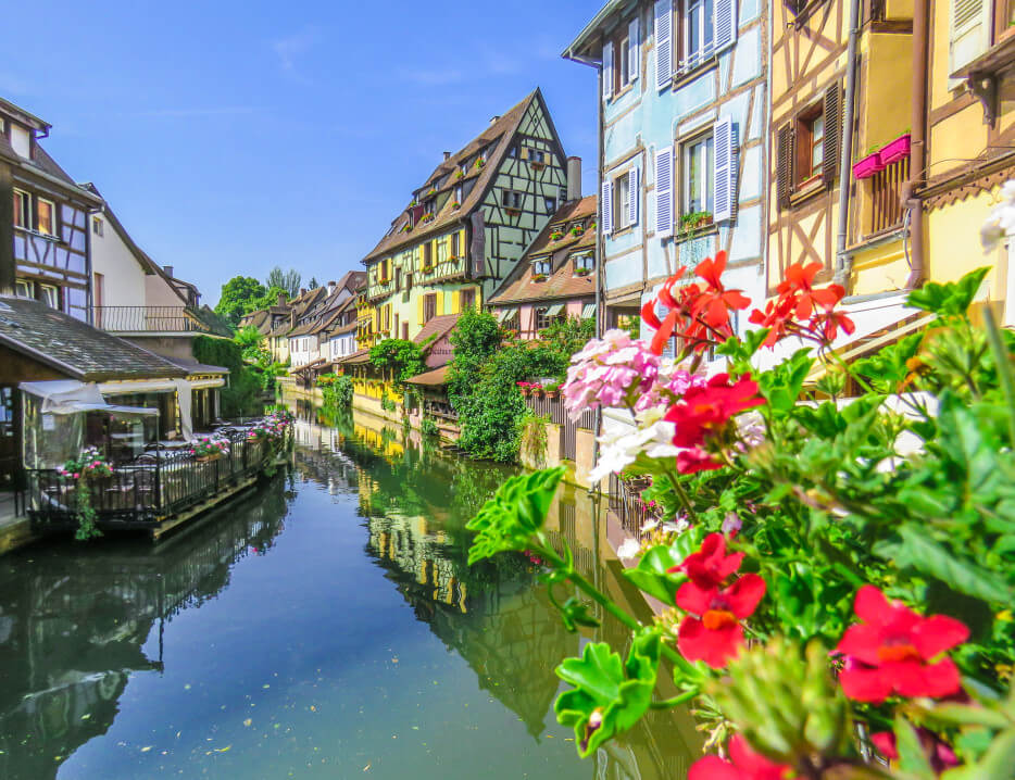 Red flowers and colorful buildings along a canal in Colmar