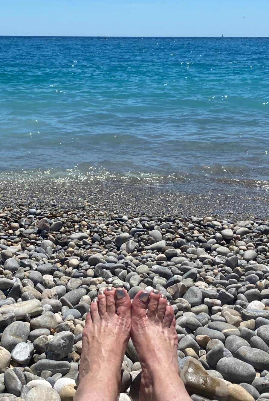 Adrian Leeds feet on the pebbled beach in Nice, France
