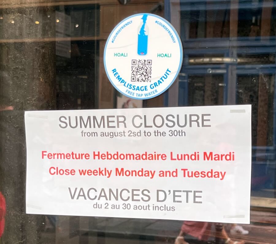 Sign in a storefront in Paris noting their summer vacation closure