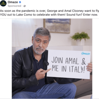 George Clooney holding poster to join him and Amal in Italy