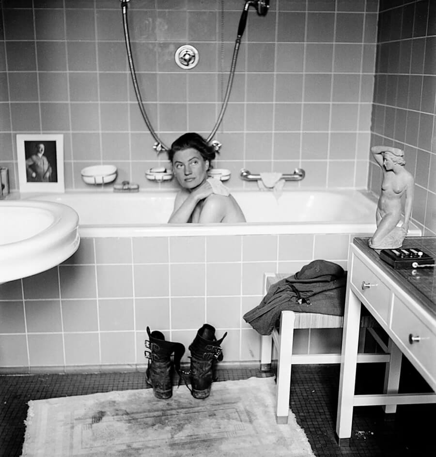 Photograph of Lee Miller in a bathtub with a photo of Hitler in the background