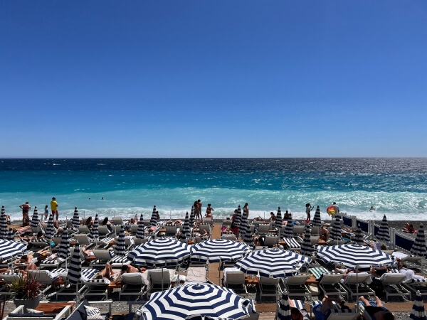 Blue and white stripped umbrellas and lounge chairs on the Beach Club in Nice, France