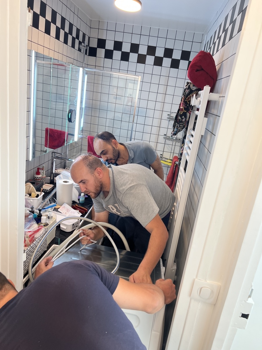 Workmen installing the washing machine in Adrian Leeds; bathroom in her renovated apartment in Paris