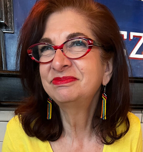Adrian Leeds in a yellow top and rainbow colored earrings