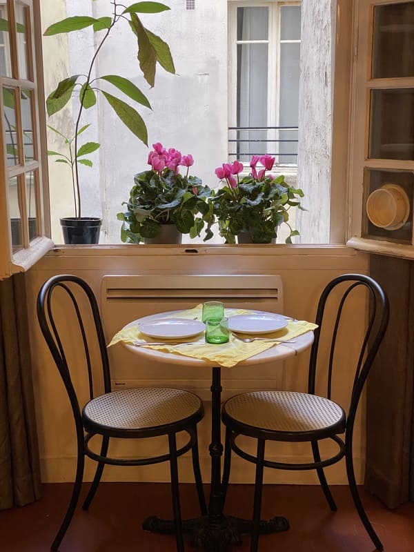 Cafe table and chairs under the window at rue François Miron