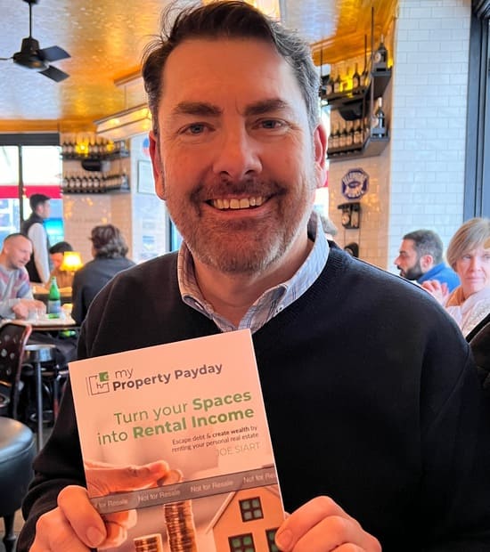 Author Joe Siart in a cafe with his book, My Property Payday, Turn your Spaces into Rental Income