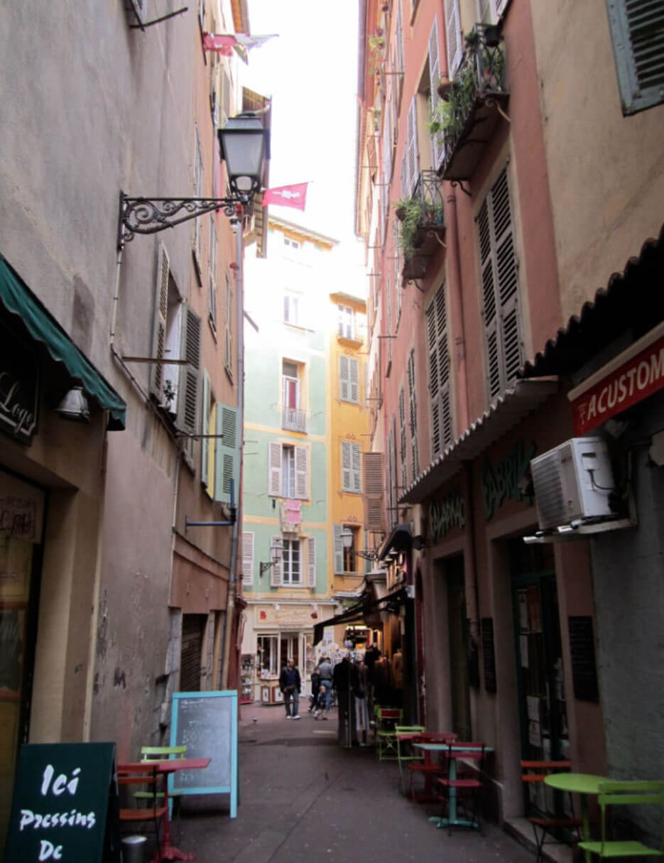Looking down a typical street lined with pastel colored buildings in Nice