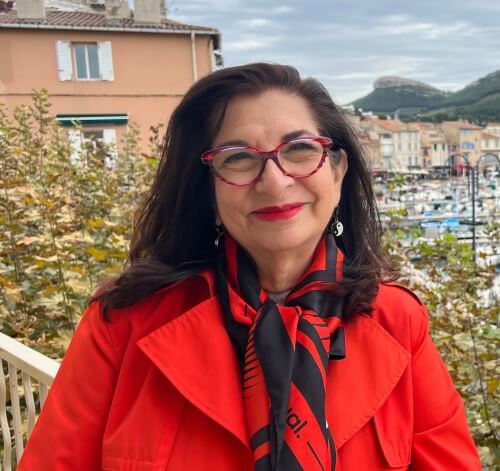 Adrian Leeds in a red coat with black and red scarf, in Cassis France