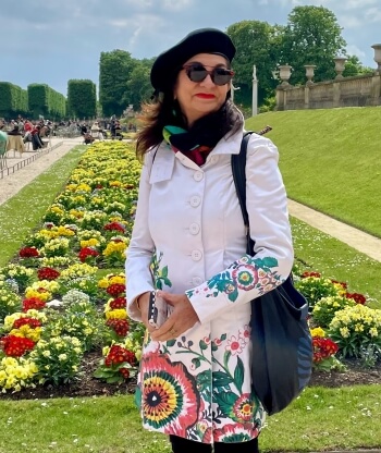 Adrian Leeds dressed in a flowery coat in a garden in Paris