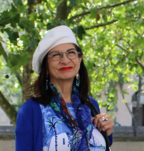 Adrian Leeds dressed in blue, wearing a white beret
