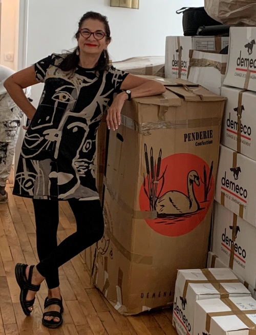 Adrian Leeds standing beside a large stack of moving boxes