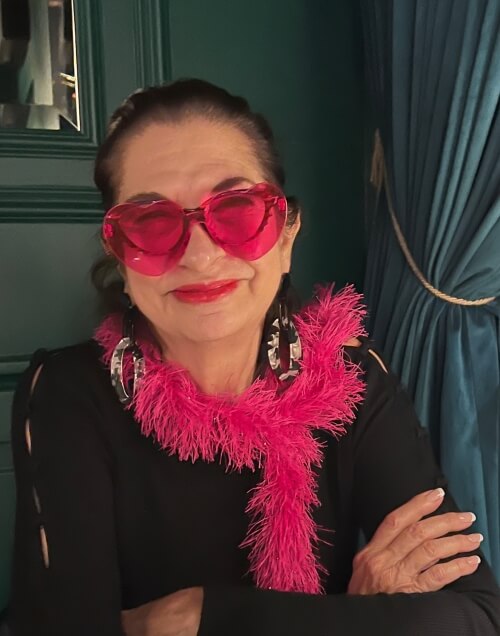 Adrian Leeds wearing pink sunglasses and a pink boa