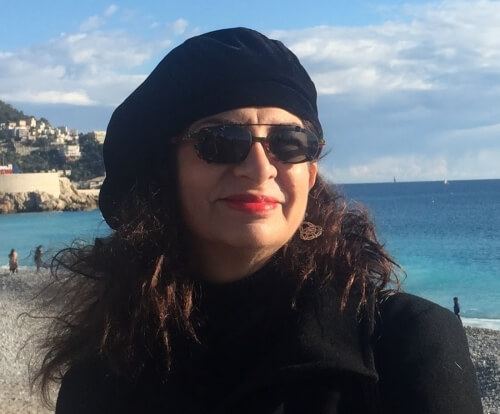 Adrian in a black jacket and black beret at the seaside in France