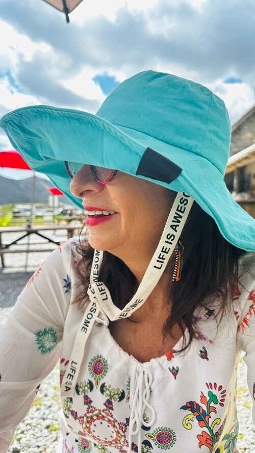 Adrian Leeds at the beach wearing a turquoise sunhat instead of her signature beret