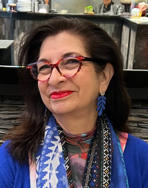 Adrian Leeds dressed in blue with blue scarf and blue earrings