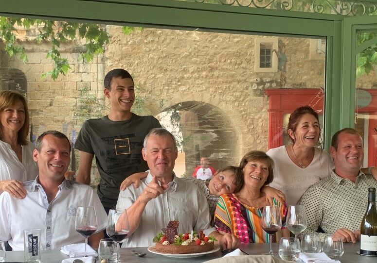 A family gathered for a family photo at a large table spread for lunch