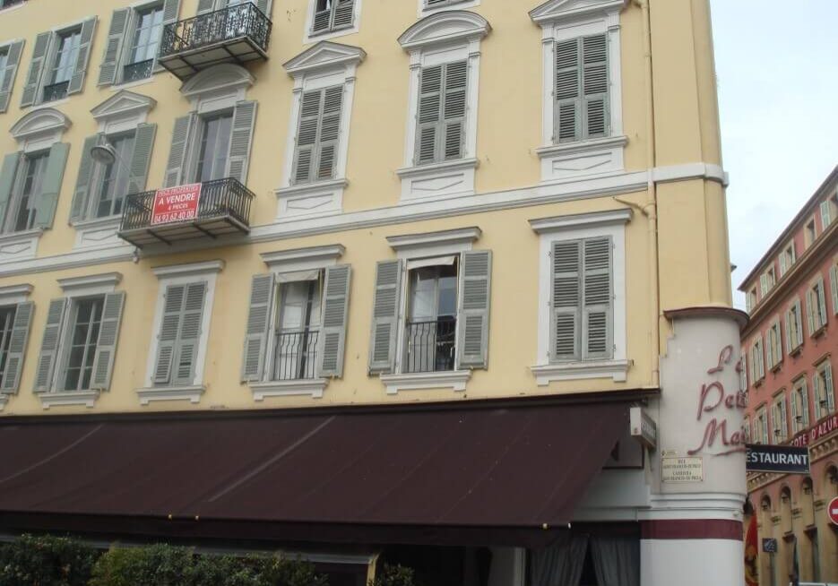 Building facade in Paris with an apartment for sale sign