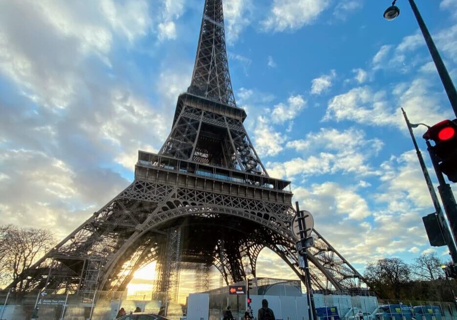 Ground level view of the Eiffell Tower in Paris, blue skies and clouds in the background