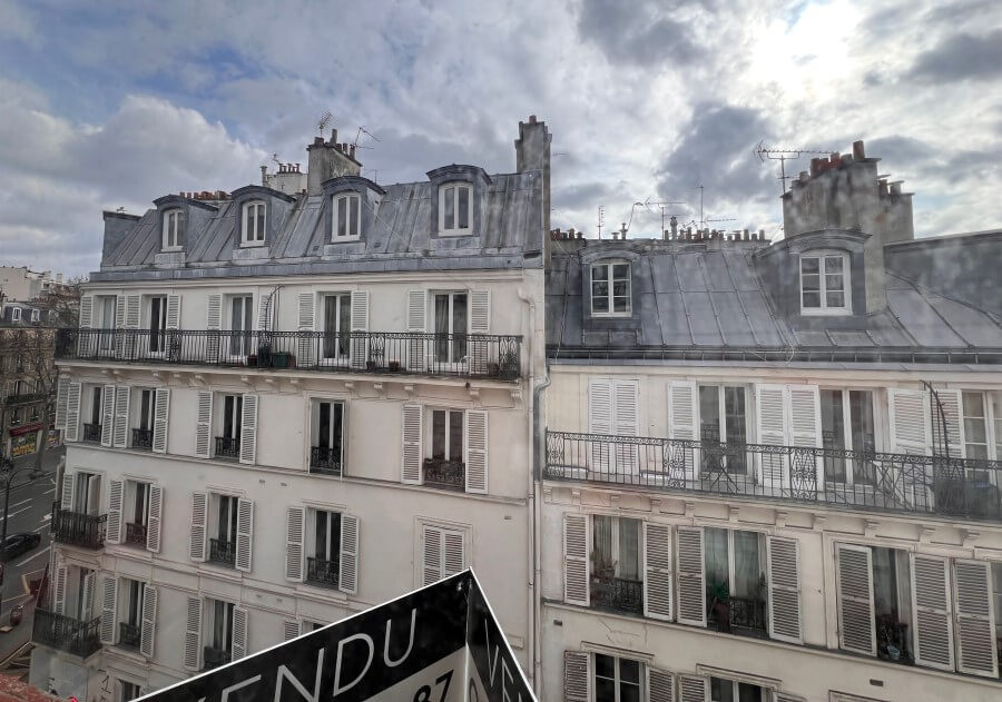 View of a Paris apartment building with a Vendue (for sale) sign on one of the apartments