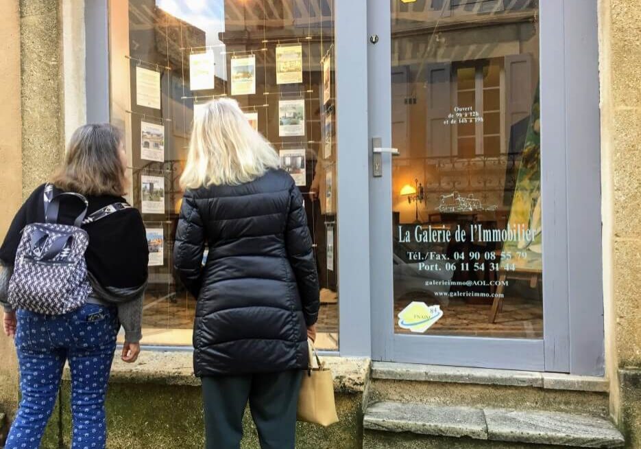 Two women staring at the property listings for a real estate agency in France