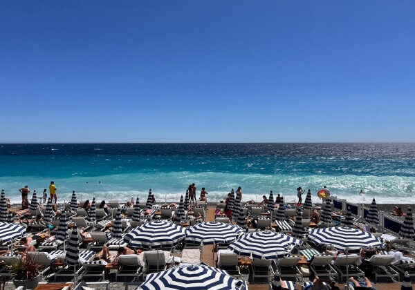 Blue and white stripped umbrellas and lounge chairs on the Beach Club in Nice, France