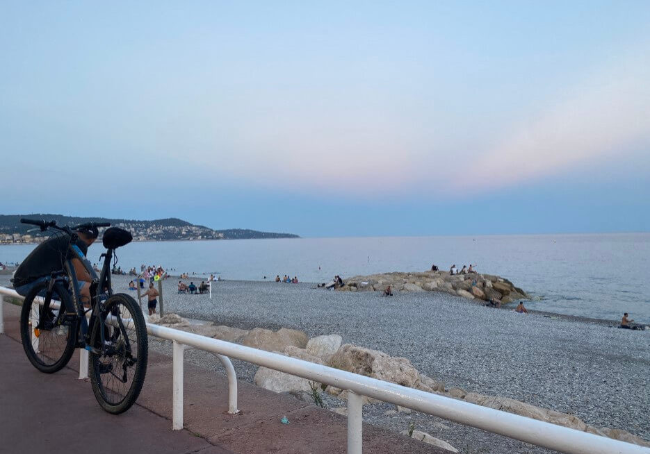 A bicyclist taking a break on the Promenade in Nice at sunset